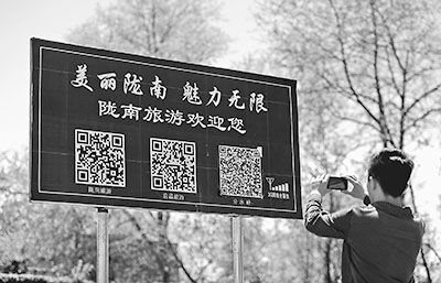 游客在甘肅省隴南市宕昌縣境內(nèi)國道212線旁用手機(jī)掃描路邊的隴南旅游二維碼 游客在甘肅省隴南市宕昌縣境內(nèi)國道212線旁用手機(jī)掃描路邊的隴南旅游二維碼